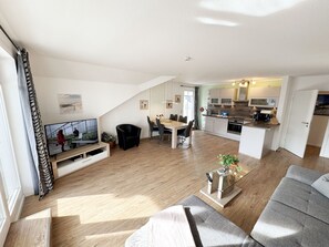 A modern apartment with a dining area, kitchen, and living room.