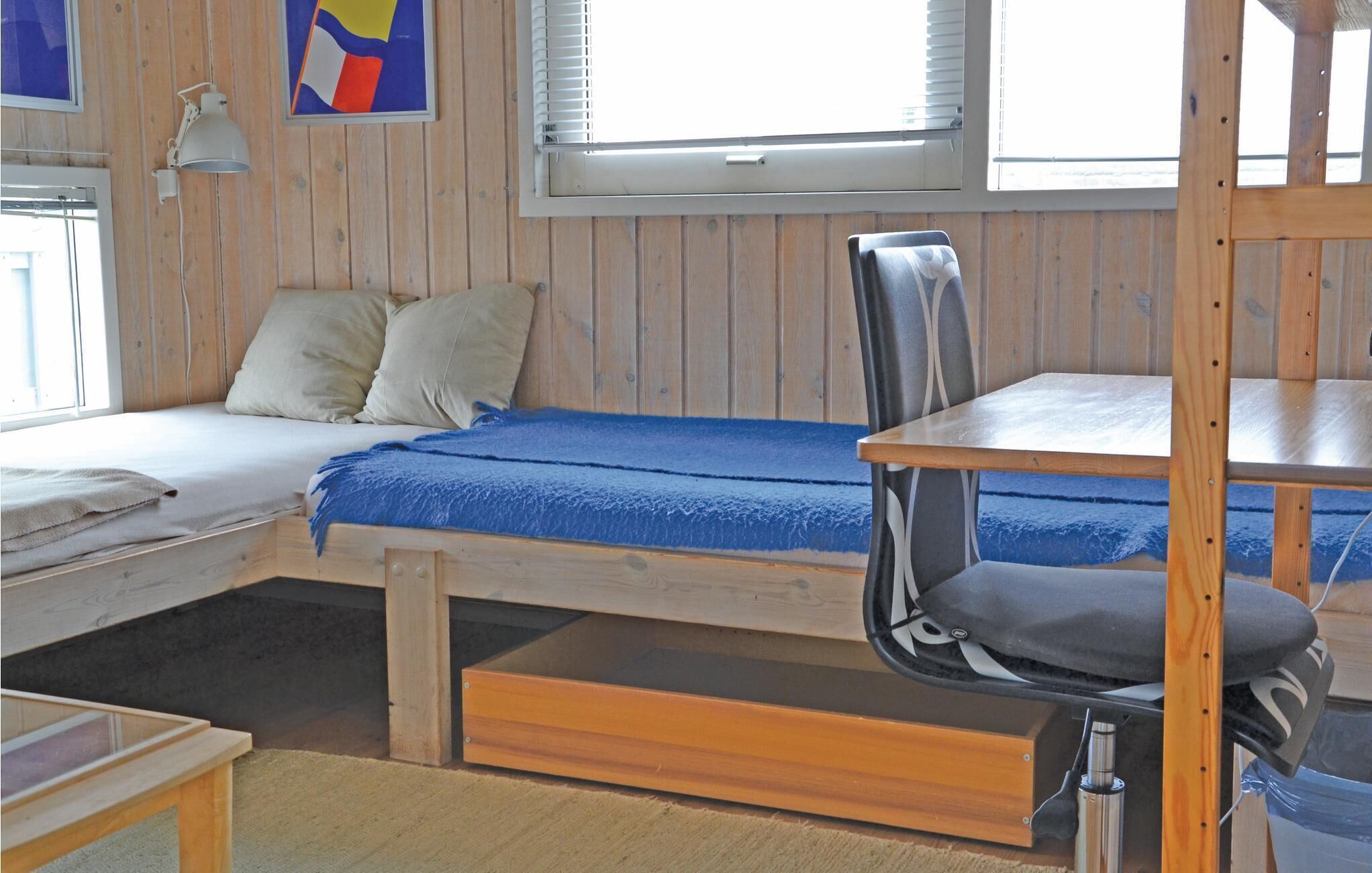 Una habitación pequeña de madera con una cama, un escritorio y una silla.