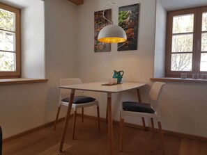 A dining area with a table, chairs, a pendant light, and a window with a view of trees. - Apartment G1 - Apartments Garhammer, Kreuth-glassworks (Kreuth)