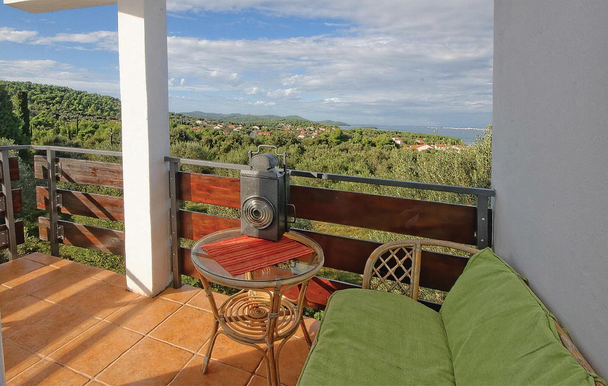 Ein Balkon mit Tisch und Stuhl, mit Blick auf eine malerische Aussicht auf ein Dorf und Hügel.
