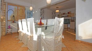 A dining area with a glass table and chairs, a chandelier, and a view of the kitchen and living area. - Awesome home in Zdrelac (Zdrelac)