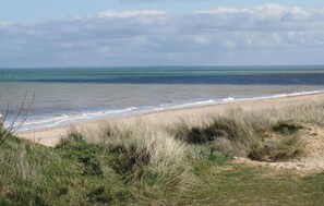 Una playa con arena y dunas cubiertas de hierba.