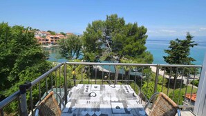 A balcony with a view of a coastal area, including a body of water and buildings in the background.