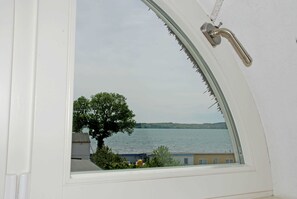 Une fenêtre donnant sur un lac, avec des bâtiments en arrière-plan.