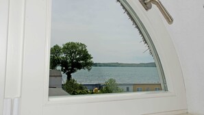 Une fenêtre donnant sur un lac, avec des bâtiments en arrière-plan.
