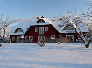 Una casa roja con techo y patio cubiertos de nieve.