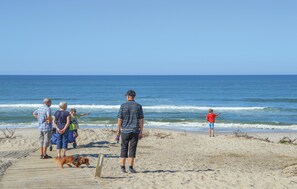 A beach scene with a wooden boardwalk, people, and a dog. - 1 bedroom nice home in Ringkøbing (Ringkøbing)