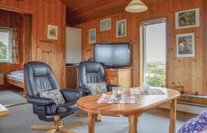 A cozy room with two leather chairs, a wooden table, a television, and framed pictures on the walls. - 1 bedroom nice home in Ringkøbing (Ringkøbing)