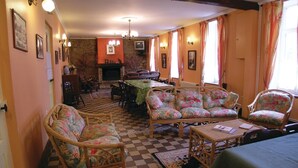 A cozy living room with a checkered floor, floral upholstered furniture, a fireplace, and a television.