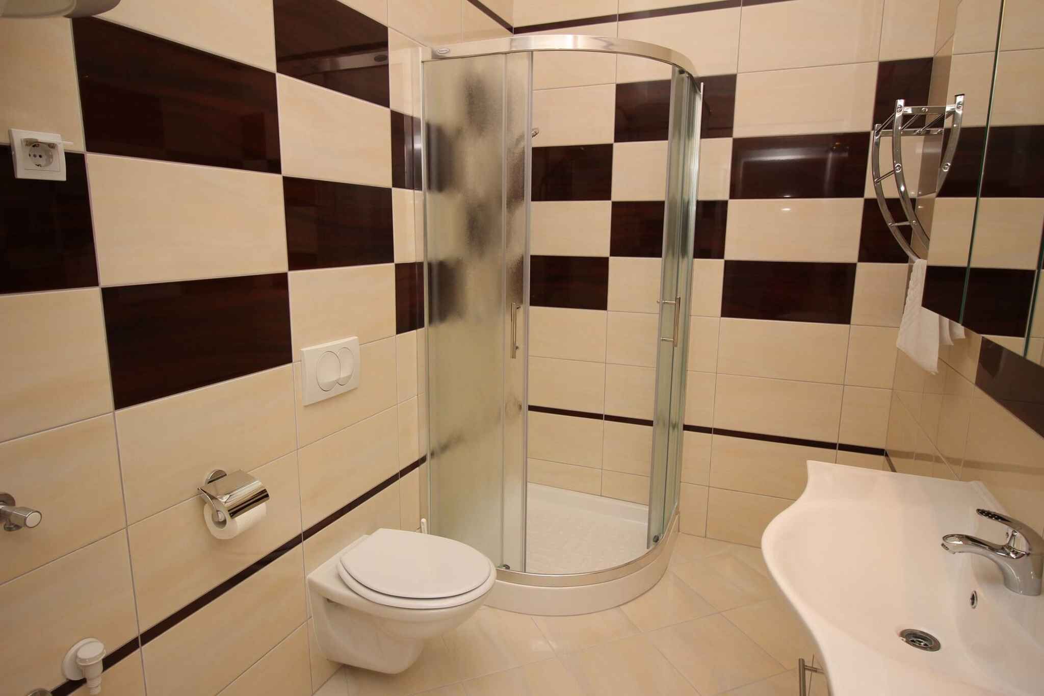 A bathroom with a glass-enclosed shower, a white toilet, and a sink with a mirror.