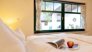 A bed with white bedding, a book, and an apple.