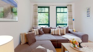 A modern living room with a sectional sofa, a coffee table, and a large window with curtains.