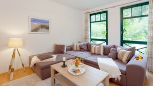 A modern living room with a sectional sofa, a coffee table, a lamp, and a window with curtains.