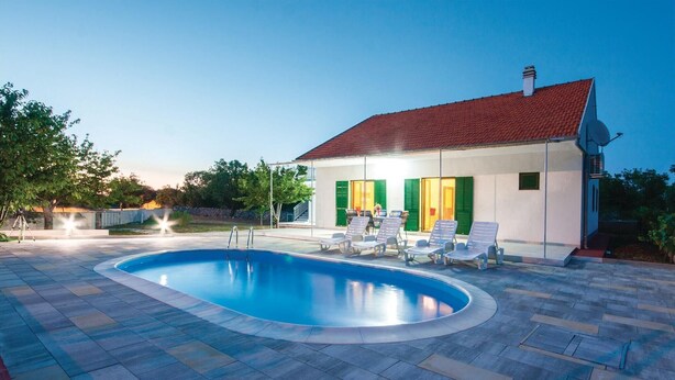 A swimming pool with lounge chairs and a house with a red roof and green shutters. - Gorgeous home in Lozovac (Lozovac)