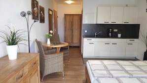 A compact room with a bed, a small dining table with chairs, a kitchenette, and a wardrobe. - (157) 1- room apartment - apartment complex Yachthafenresidenz (Kühlungsborn)