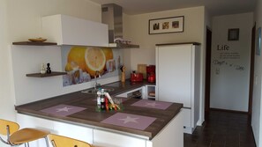 Una cocina con una isla central, un refrigerador y una pared con una frase motivacional.