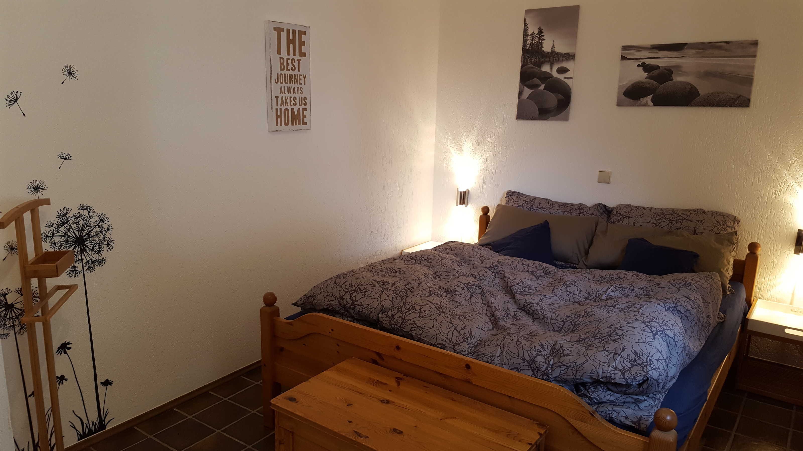 A bedroom with a wooden bed, a nightstand, a bedside table, and wall art.