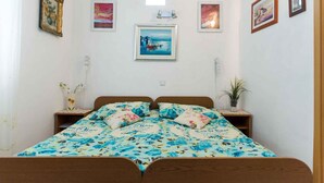 Un dormitorio con cama, dos mesitas de noche y una repisa en la pared.