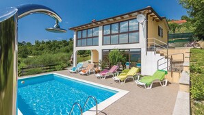 Ein modernes Gebäude mit zwei Etagen, einem Swimmingpool, Liegestühlen im Freien und einer Satellitenschüssel.
