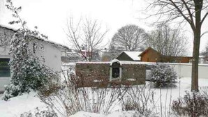 A snow-covered outdoor area with a stone wall, a small wooden structure, and leafless trees. - Apartment 3 - Bluehouse - Apartments Egonschultz (Zempin)