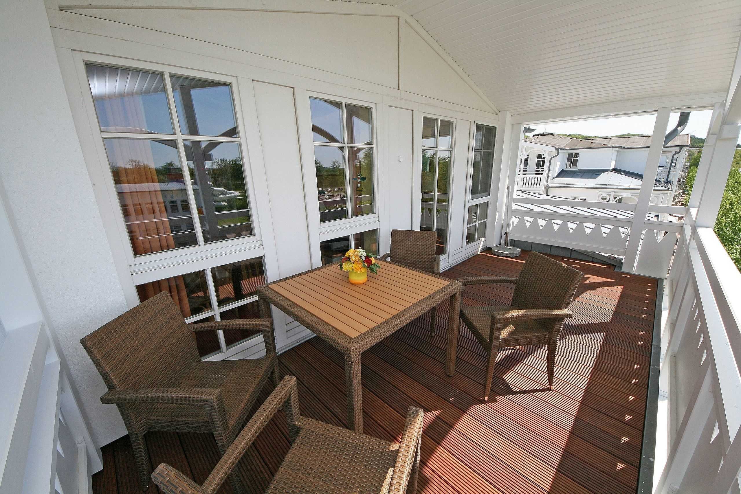 Un espace extérieur aménagé avec une table et des chaises, protégé par un toit, de grandes fenêtres et une vue sur un bateau.