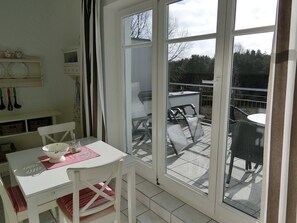 Ein Zimmer mit Tisch, Stühlen, einem Fenster und Blick nach draußen.