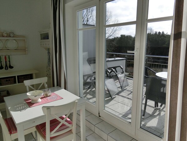 Ein Zimmer mit Tisch, Stühlen, einem Fenster und Blick nach draußen.