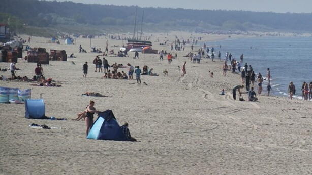 Una playa con tiendas de campaña y gente.