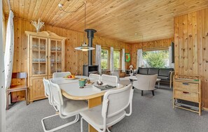 A cozy cabin interior with a dining area, a sofa, and a fireplace. - 2 bedroom beach front home in Bindslev (Bindslev)