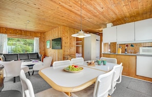 A modern, compact living space with a wooden interior, a dining area with a fruit bowl, and a kitchenette. - 2 bedroom beach front home in Bindslev (Bindslev)