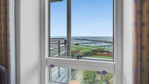 A view from a window overlooking a coastal area with a pier and a grassy area with a flower vase.