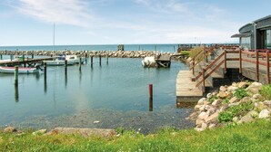 A marina with boats docked, a wooden pier, and a building with a red railing.