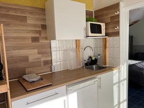 A compact kitchen with a microwave, sink, and wooden countertop.
