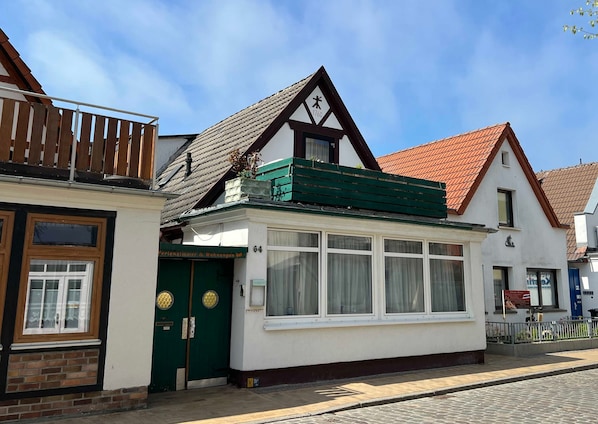 A traditional building with a green door, white windows, and a red-tiled roof.
