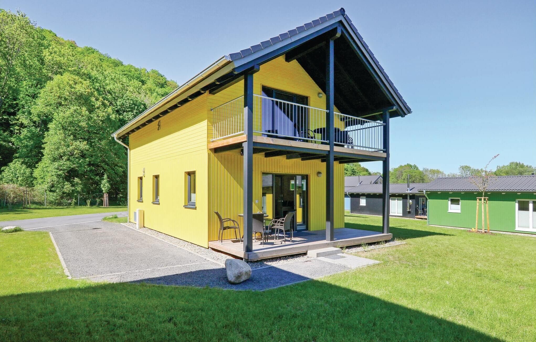 Ein gelbes, zweistöckiges Gebäude mit Balkon, überdachter Terrasse und Schotterauffahrt.