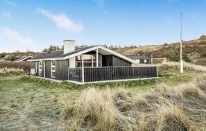 A modern house with a sloped roof, large windows, and a wooden deck. - 3 bedroom beautiful home in Hjørring (Hjørring)