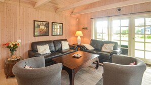 Ein gemütliches Wohnzimmer mit Holzvertäfelung, zwei Sofas, einem Couchtisch und einer Lampe.