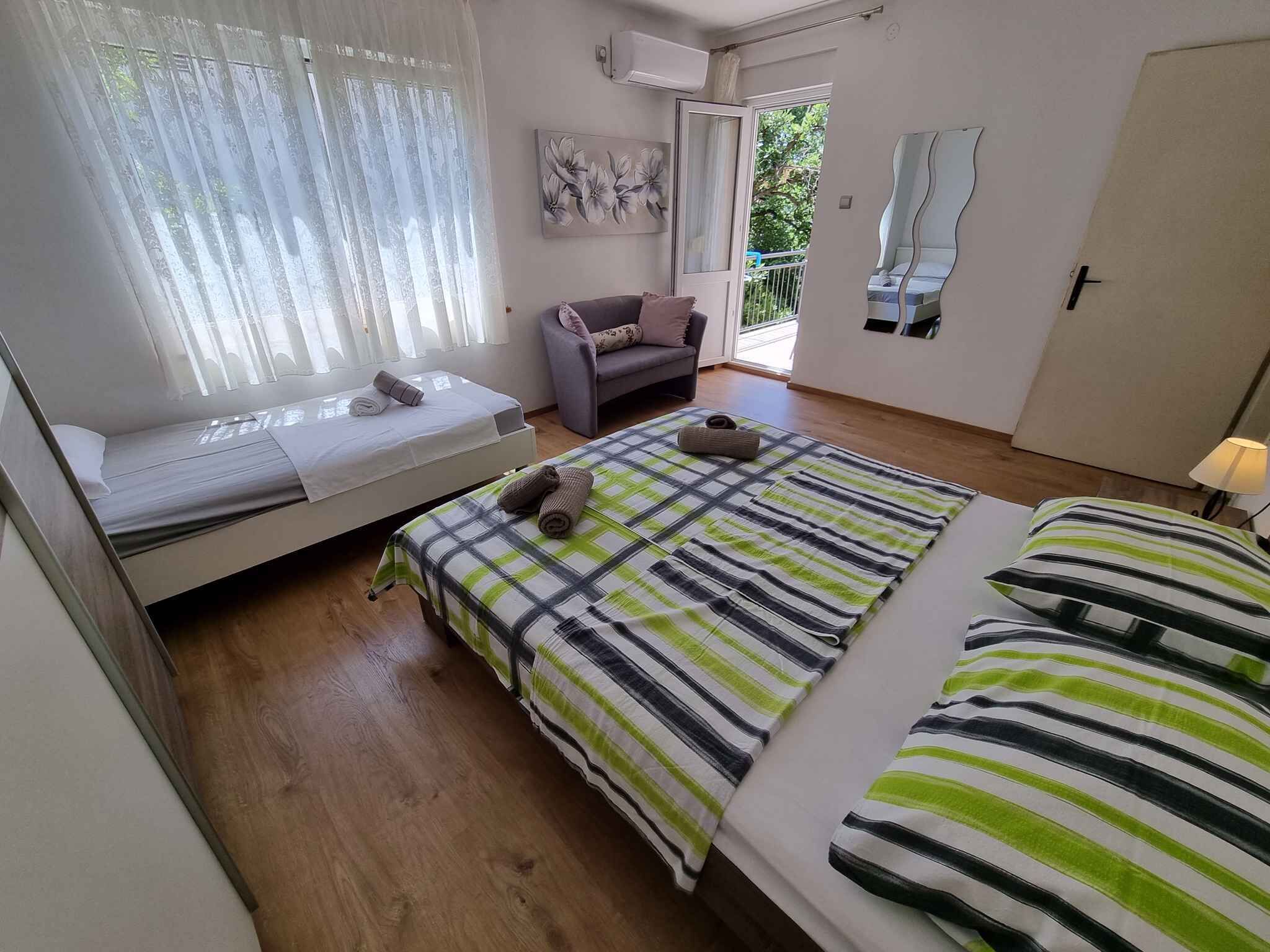 Ett sovrum med en säng, en soffa, ett fönster med gardiner, en tavla och en dörr.