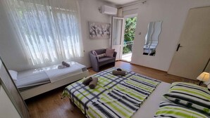 Une chambre à coucher avec un lit, un canapé, une fenêtre avec des rideaux, un tableau et une porte.