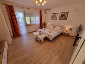 Un dormitorio con cama, mesitas de noche, escritorio y ventana con cortinas.