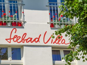 En bygning med et skilt der viser 'Feebad Villa' og balkoner med røde blomster.