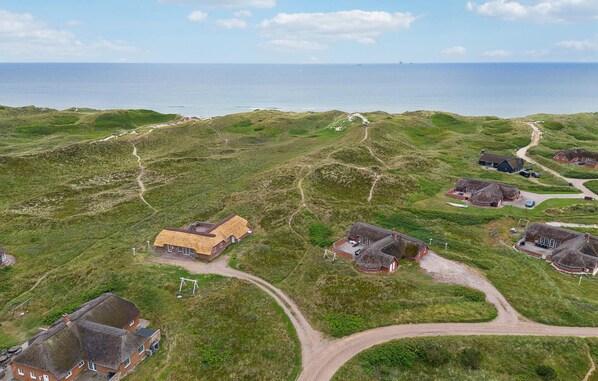 A coastal village with thatched-roof houses, a winding road, and a view of the sea.