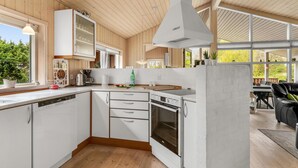 Et moderne køkken med hvide skabe, en indbygget ovn og spiseområde med en sort lædersofa.