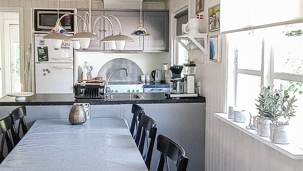 Una cucina con tavolo da pranzo, sedie, un fornello e diversi elettrodomestici.