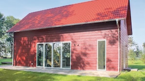 En röd träbyggnad med ett sluttande tak och stora glasfönster.