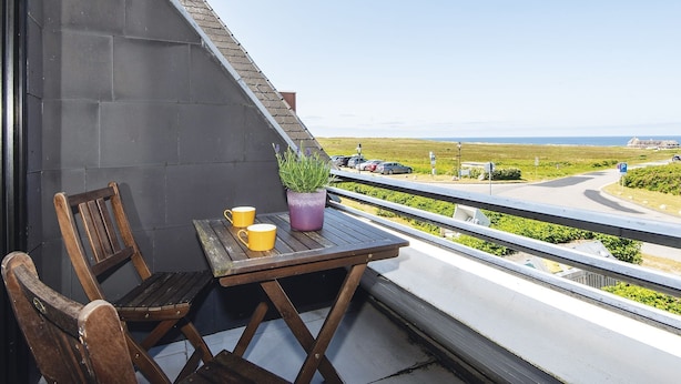 A balcony with a wooden table, two chairs, and a potted plant. - Nautilus 12 from A&M - Nautilus 12 (Kampen (Sylt))