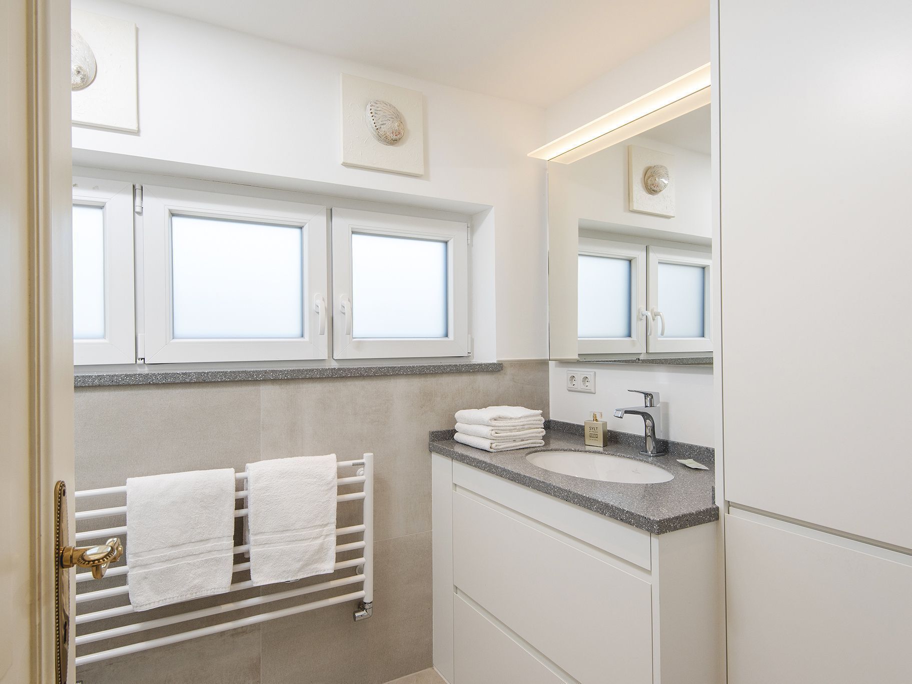 A modern bathroom with a white vanity, a sink, and a towel rack.