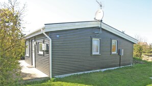 Een klein, gelijkvloers vakantiehuisje met een schotelantenne, een deur en twee ramen.