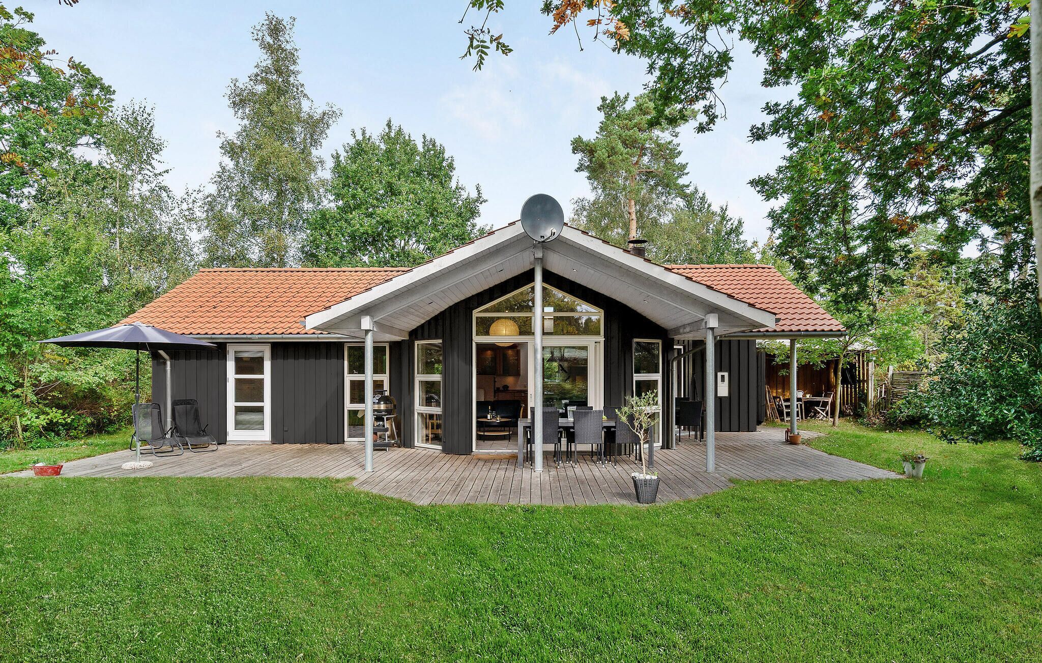 Ett modernt hus med ett sluttande tak, en täckt uteplats och ett stort fönster.
