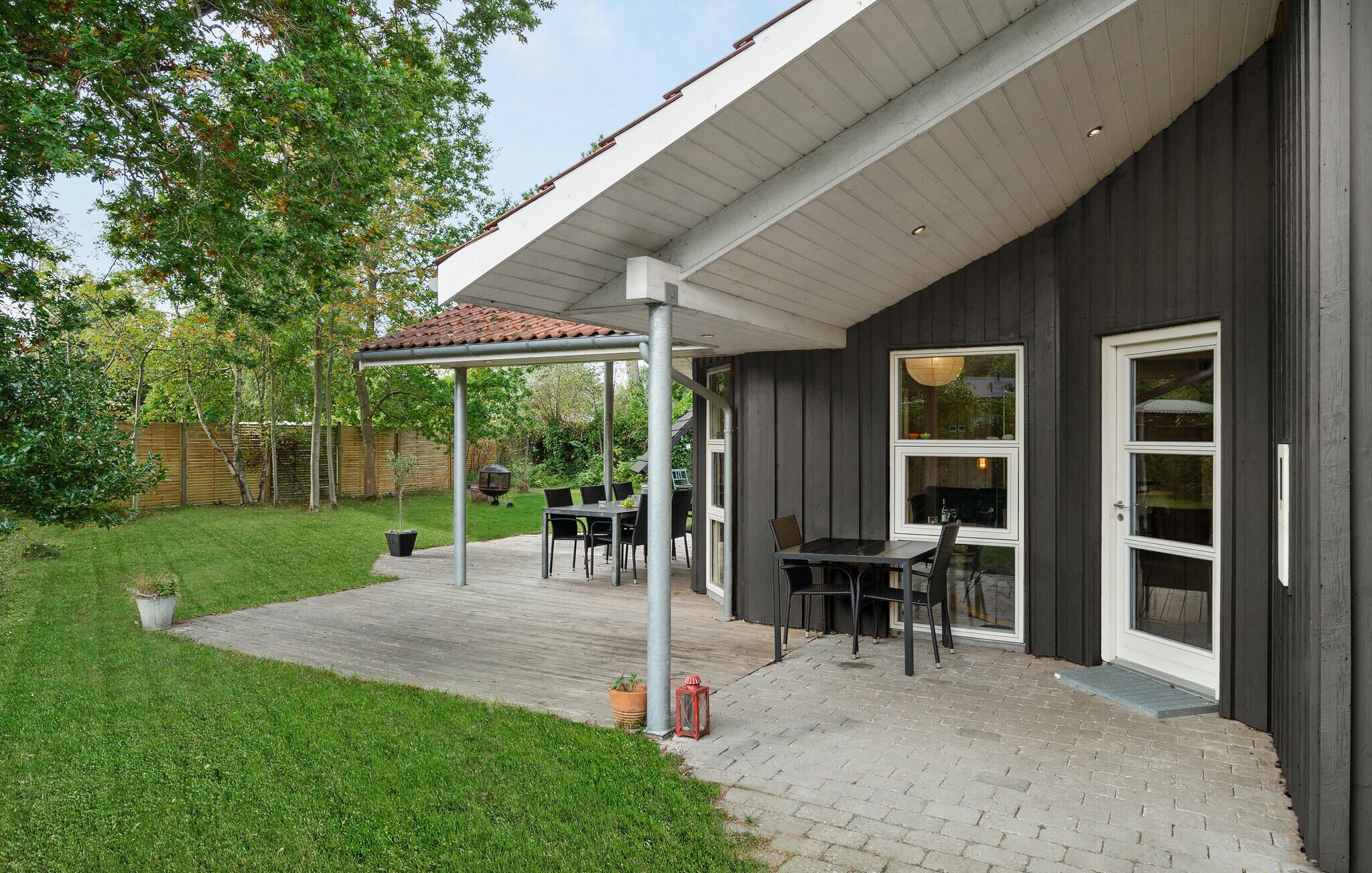 A covered patio with a table and chairs, a pergola, and a view of the backyard.